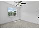 A serene bedroom features a ceiling fan, light gray carpet and a window with views of mature trees at 140 E End Ave # 2, Durham, NC 27703