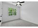 This light-filled bedroom features light gray carpet, a ceiling fan and a window with views of mature trees at 140 E End Ave # 2, Durham, NC 27703