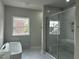 Elegant bathroom featuring soaking tub, glass shower, and marble-look tiling at 1400 Gathering Park Cir # 202, Cary, NC 27519