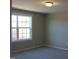 Cozy bedroom featuring neutral walls, plush carpeting, and a single, large window at 1415 Reading Ct # 77Kl, Burlington, NC 27217