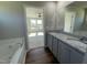 The well-lit bathroom features double sinks, granite countertops, gray cabinets, a tub, and luxury vinyl flooring at 181 Pate Landing Dr, Selma, NC 27576