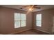 Cozy bedroom with neutral tones, carpet flooring, ceiling fan, and two windows providing ample natural light at 1828 Parkside Village Dr, Clayton, NC 27520
