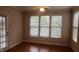 Cozy bedroom featuring a ceiling fan, wood floors, and three windows with ample natural light at 1828 Parkside Village Dr, Clayton, NC 27520