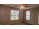 Cozy bedroom with neutral tones, carpet flooring, ceiling fan, and two windows providing ample natural light at 1828 Parkside Village Dr, Clayton, NC 27520