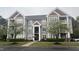 View of the gray home exterior showcasing mature trees, manicured lawns, and multiple window views at 1828 Parkside Village Dr, Clayton, NC 27520