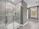 Modern bathroom featuring tiled shower with glass door and a view of the outdoors through a window at 3402 Pelican Ln, Durham, NC 27703