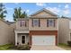 Two-story home featuring tan siding, brick accents, a two-car garage and tidy landscaping, under a blue sky at 434 Golden Villas Dr, Rocky Mount, NC 27809