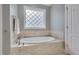 Relaxing bathroom featuring a soaking tub with tile surround and natural light from a decorative window at 659 Willard Dr, Creedmoor, NC 27522