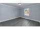 Bedroom with gray wood-look floors, neutral paint, and a window overlooking the front yard at 1729 Augustus Dr, Rocky Mount, NC 27801