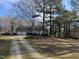 Home showcasing a long driveway, two-car garage, and covered porch, surrounded by mature trees and landscaping at 2010 Twin Acres Rd, Clayton, NC 27520