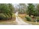 Home nestled among mature trees with a long gravel driveway and a well-maintained front yard at 2010 Twin Acres Rd, Clayton, NC 27520