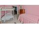 A charming pink bedroom with a bunk bed, twin bed, and vintage dresser at 219 N Richardson Ave, Nashville, NC 27856