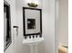 Elegant powder room featuring a pedestal sink, framed mirror, and modern lighting fixtures at 4073 Elk Creek Ln, Raleigh, NC 27612