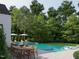 Inviting pool area with outdoor dining and lounge seating surrounded by mature trees and manicured landscaping at 5301 Inglewood Ln, Raleigh, NC 27609