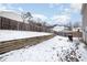 Snowy backyard featuring a retaining wall, partial privacy fence, and outdoor grill at 5627 Quitman Trl, Raleigh, NC 27610