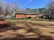 Wide shot of the property's rear, showcasing a spacious backyard with a wooden deck and mature trees at 613 Sexton Ave, Zebulon, NC 27597