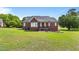 Spacious backyard with green grass, featuring a brick house with a cozy back porch at 105 Pinecrest Dr, Angier, NC 27501