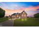 Exterior dusk shot of brick home with landscaped front yard, lights, and long curved driveway at 105 Pinecrest Dr, Angier, NC 27501