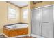 Bathroom with a jacuzzi tub, a shower with glass doors, and two windows at 1175 Faulkner Town Rd, Henderson, NC 27537