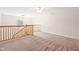 Upstairs loft area with neutral carpet, a wooden railing, and natural light from an arched window at 1175 Faulkner Town Rd, Henderson, NC 27537