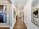 Bright hallway featuring hardwood floors, white trim, and artwork on the walls leading to an open-concept living space at 1712 Red Roses Ave, Durham, NC 27703