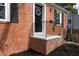 Close-up of the front door and landing with brick and a small black iron railing at 2204 Guess Rd, Durham, NC 27705