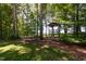Backyard treehouse with play area, surrounded by mature trees and natural landscape at 2209 Woodnell Dr, Raleigh, NC 27603