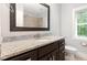 Bathroom vanity with dark cabinets, granite countertops, and a big mirror at 2209 Woodnell Dr, Raleigh, NC 27603