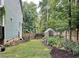 Garden area with mulch, plants, greenery, enclosed by a wooden fence, and a greenhouse at 2209 Woodnell Dr, Raleigh, NC 27603