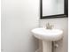A powder room with a pedestal sink and a framed mirror with neutral walls at 2209 Woodnell Dr, Raleigh, NC 27603