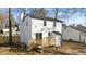 Backyard view of a white house with a new wooden deck and stairs, set against a backdrop of tall trees at 2908 Basswood Dr, Raleigh, NC 27610