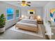 Bright bedroom featuring a ceiling fan, a wooden bed frame, and large windows with scenic views at 3300 Mossdale Ave, Durham, NC 27707