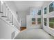 Bright foyer featuring a staircase with white railings and an abundance of natural light from large windows at 3300 Mossdale Ave, Durham, NC 27707