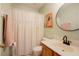 Cozy bathroom features a shower with curtain and a vanity with round mirror at 3320 Derbyshire Pl, Raleigh, NC 27604