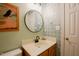 Bathroom featuring single sink vanity, round mirror, and decorative wallpaper at 3320 Derbyshire Pl, Raleigh, NC 27604