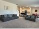 An open-concept living room boasts gray sofas, an open stairway, and a view of the kitchen and dining area at 704 Mirror Pond Dr, Zebulon, NC 27597