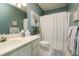 A well-lit bathroom featuring a toilet, vanity with sink, and shower with a white curtain at 103 Bruce Dr, Cary, NC 27511