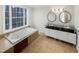 Luxurious bathroom with a jacuzzi tub, dual sinks, and large window at 11308 Leesville Rd, Raleigh, NC 27613