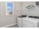 Bright laundry room with a window, washer, dryer, overhead storage shelf, and sleek gray tiling at 155 Jade St, Smithfield, NC 27577