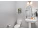 Elegant half-bath with pedestal sink, round mirror, and modern fixtures in a neutral color palette at 192 Kensington Dr, Spring Lake, NC 28390