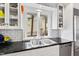 Close-up on a kitchen sink with granite countertops and white cabinets and open shelving at 2147 Wake Dr, Raleigh, NC 27608