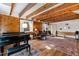 Inviting living room with wood-paneled walls, exposed beams, and a grand piano at 2147 Wake Dr, Raleigh, NC 27608