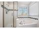 Bathroom featuring a glass shower door, tiled tub, and a bright window with blinds at 5302 Silkwood Dr, Durham, NC 27713