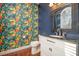 A unique powder room with bold floral wallpaper, black vanity, and hard wood floors at 5302 Silkwood Dr, Durham, NC 27713