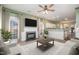 Cozy living room with a fireplace, ceiling fan, and a view through large bright windows at 5302 Silkwood Dr, Durham, NC 27713