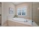 Serene bathroom featuring a large tub surrounded by tile, and a view from a window at 6824 Palaver Ln, Cary, NC 27519