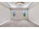 Spacious bedroom featuring plush carpet, tray ceilings and a ceiling fan with natural light from two windows at 9230 Bear Run Ln, Middlesex, NC 27557