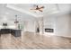 Open-concept space with fireplace, tray ceiling, view into the kitchen island, and laminate flooring at 9230 Bear Run Ln, Middlesex, NC 27557