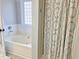 Well-lit bathroom featuring a tub with a white tiled backsplash and stylish shower curtain at 228 Kentucky Dr, Archer Lodge, NC 27527