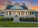 Inviting two-story home with a spacious front porch, manicured landscaping, and a vibrant sunset backdrop at 304 Ashley Woods Ct, Clayton, NC 27527